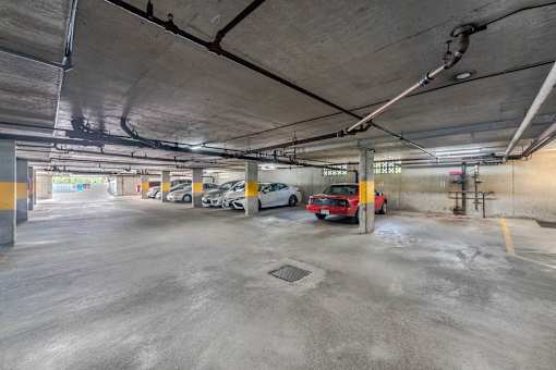 A parking garage with a red car parked in the middle.