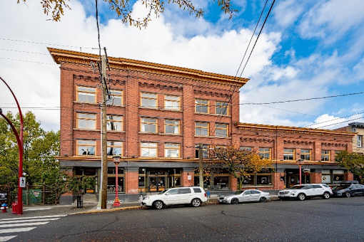 A red brick building with a white car parked in front.