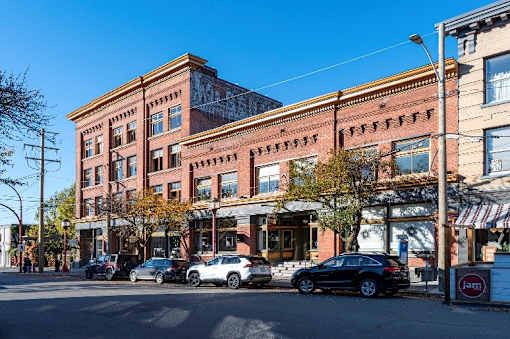 A street view of a row of buildings with cars parked in front.