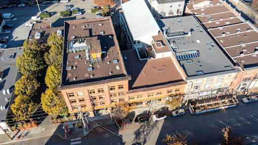 A large building with a red roof is surrounded by other buildings and trees.