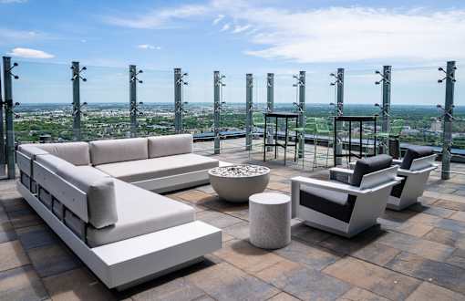 A set of outdoor furniture is arranged on a patio with a cityscape view in the background.