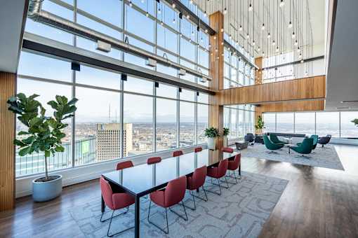 A conference room with a long table and chairs with a view of the city outside the window.