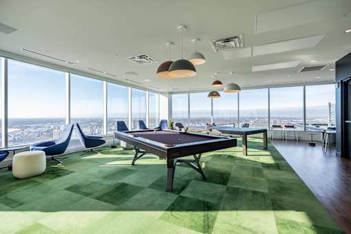 A room with a pool table and a green carpet.