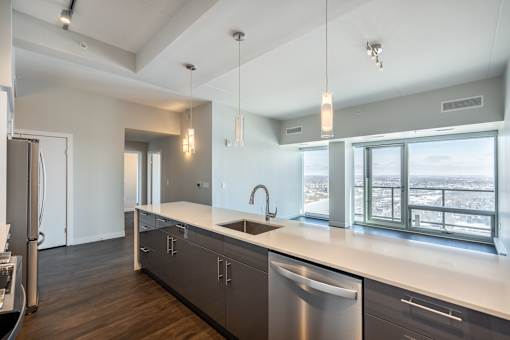 A modern kitchen with a stainless steel dishwasher and a large window overlooking the city.