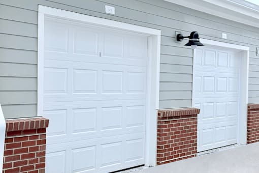Two white garage doors with brick pillars.