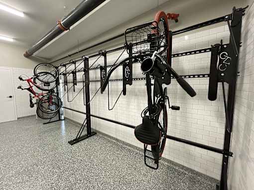 a workout room with bikes hanging on the wall and weights on a rack
