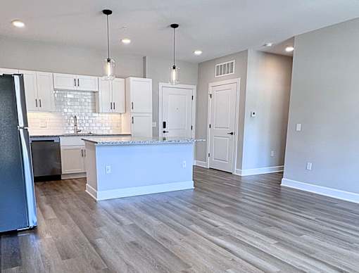 A kitchen with a white island and wooden floors.