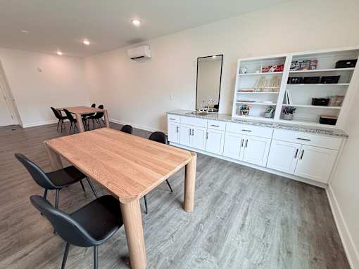 A room with a table and chairs and a cabinet with shelves.