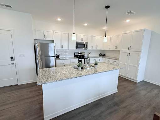 A kitchen with white cabinets and a granite countertop.