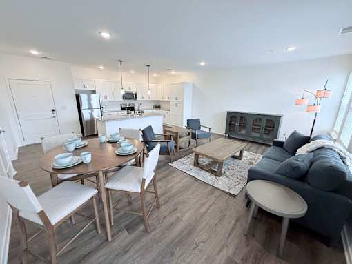 A modern dining room with a table set for six and a couch with a throw blanket on it.