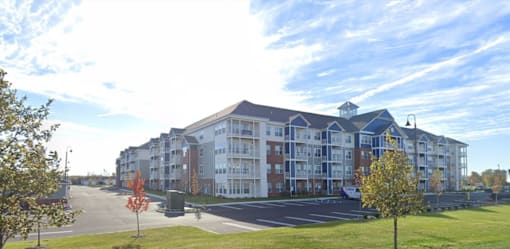A large apartment complex with a parking lot in front.