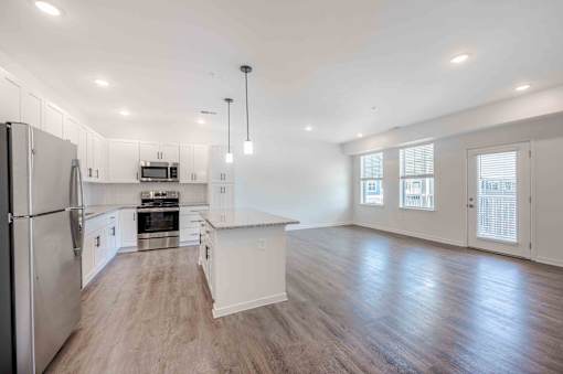 A spacious kitchen with white cabinets and a stainless steel refrigerator.