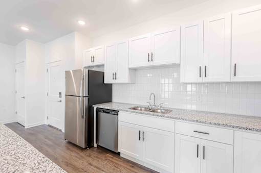 A kitchen with white cabinets and a black fridge.