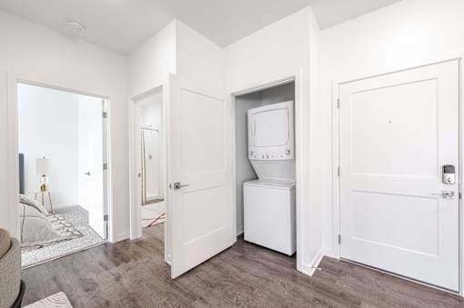 A white kitchen appliance is in a white cabinet in a white room.