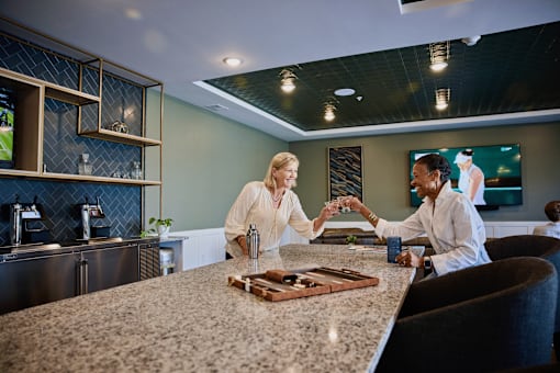 Two people shaking hands over a counter in a modern kitchen.
