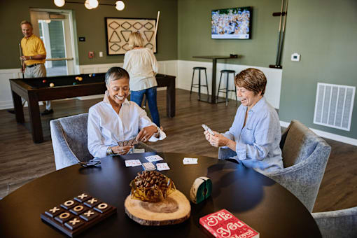 Three people playing a board game in a room with a pool table.