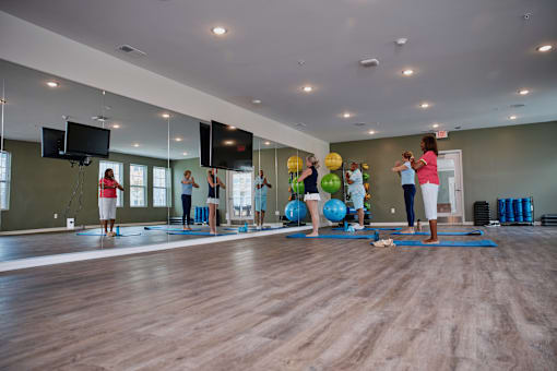 A group of people are practicing yoga in a spacious room.