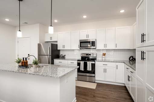 A modern kitchen with white cabinets and stainless steel appliances.