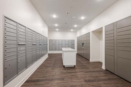 A long hallway with a white box in the middle and a row of mailboxes on the left.