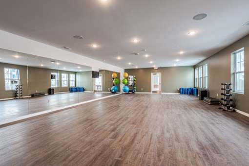 A spacious room with wooden floors and exercise equipment.
