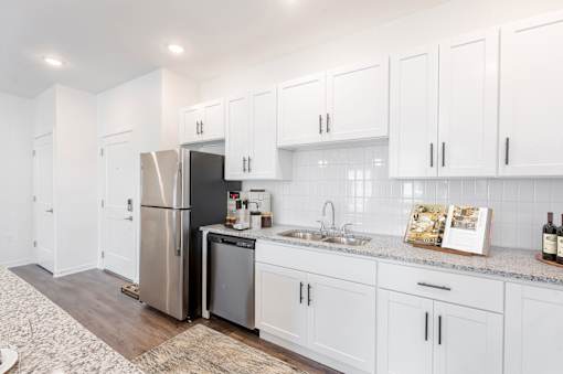 A kitchen with white cabinets and a stainless steel refrigerator.