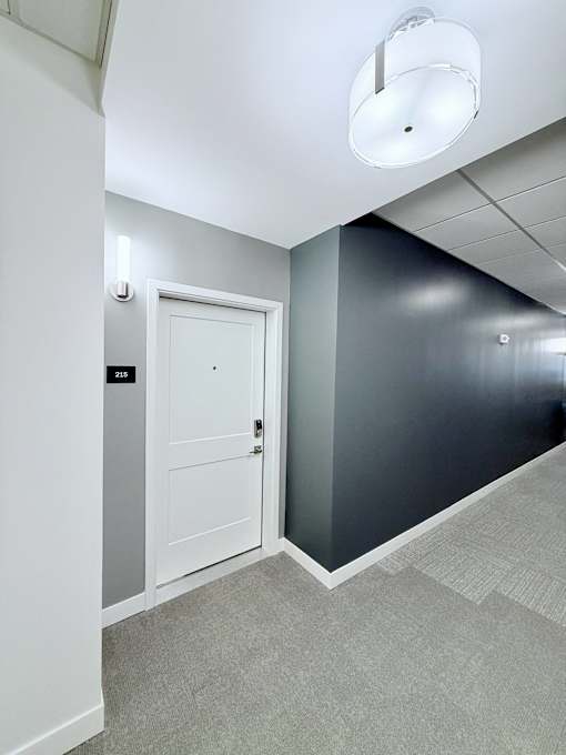 A white door is in a room with a grey carpet.