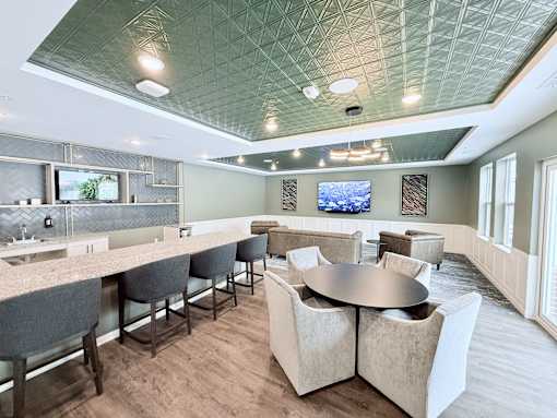 A modern dining room with a bar area and a television mounted on the wall.