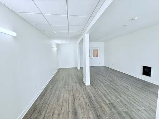A spacious room with wooden flooring and white walls.
