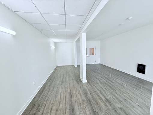 A spacious room with wooden flooring and white walls.