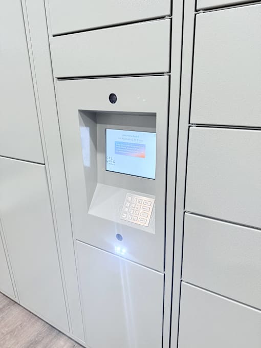 A white ATM machine with a screen and keypad.