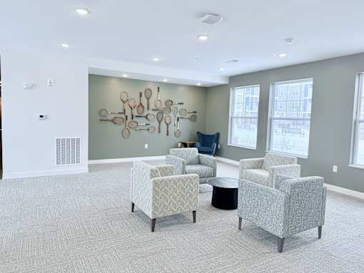 A modern waiting room with grey chairs and a large artwork on the wall.