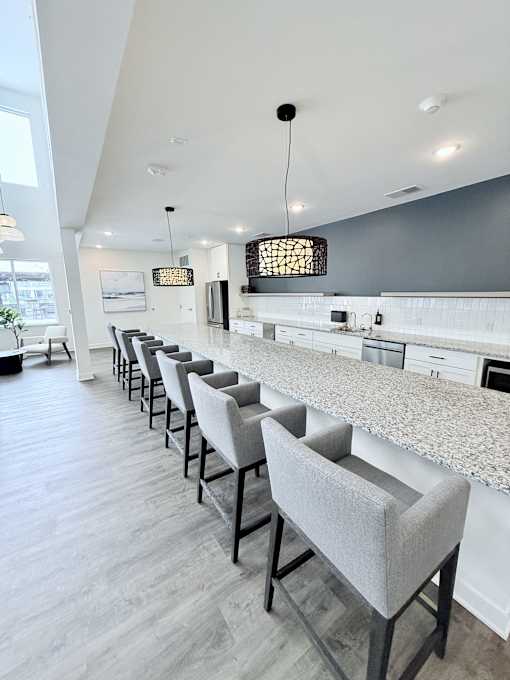 A row of grey chairs are lined up in a kitchen.