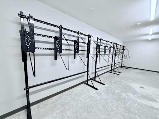 A set of black pull-up bars are lined up against a white wall.