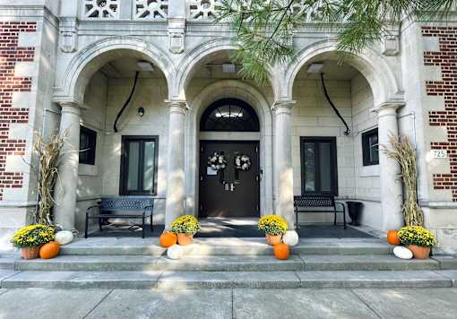 A building with a black door and windows is decorated with pumpkins and plants.