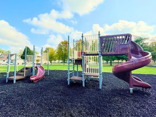 A playground with a red slide and a grey slide.