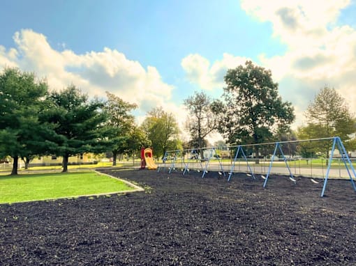 A playground with a slide and swings in a park.