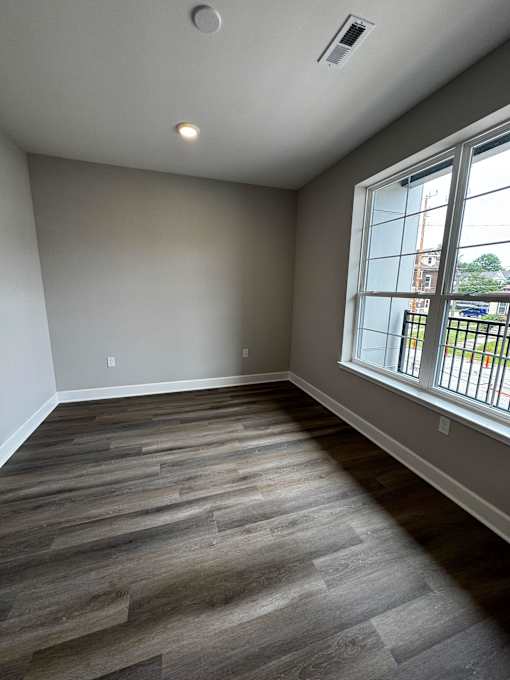 A room with a large window and wooden flooring.