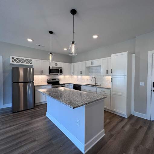 A modern kitchen with a granite countertop and stainless steel appliances.