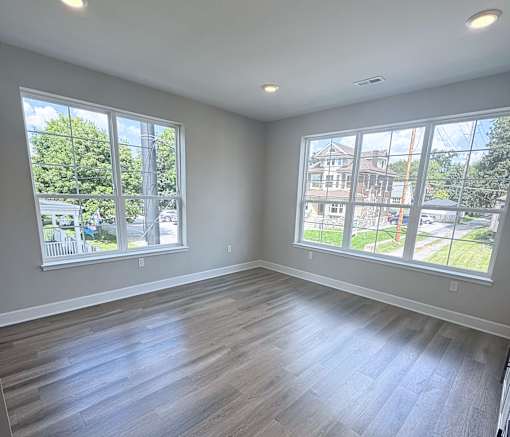 A room with two large windows and wooden flooring.