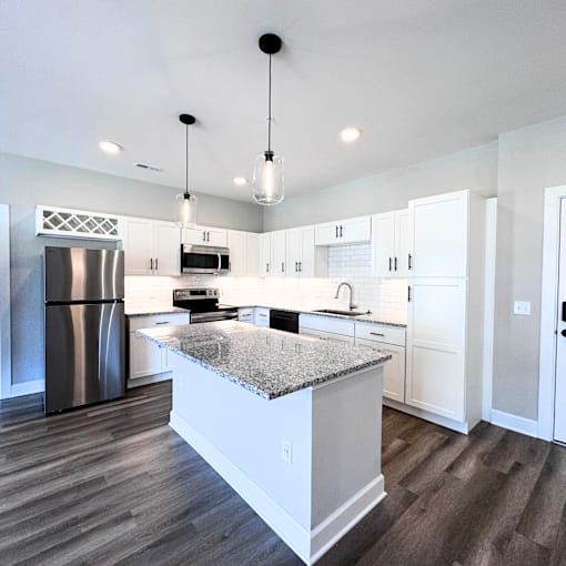 A modern kitchen with a granite countertop and stainless steel appliances.