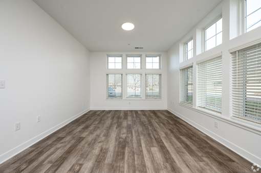 A room with wooden flooring and large windows.