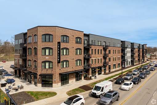 A street view of a row of modern buildings with cars parked in front.