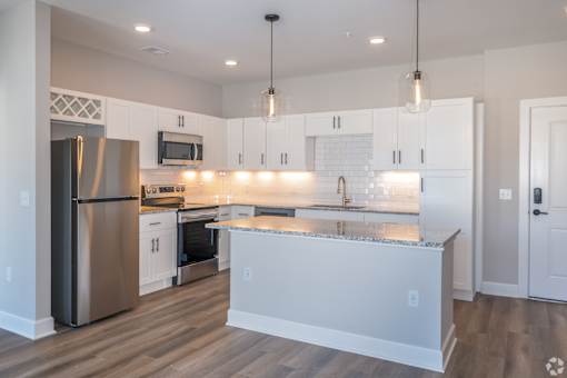A modern kitchen with a granite countertop and stainless steel appliances.