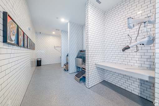 A bathroom with white tiled walls and a white bench.