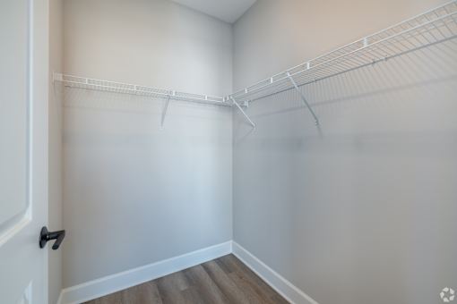 A white closet with a door and shelves.