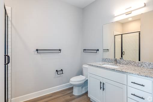 A bathroom with a toilet, sink, and towel racks.