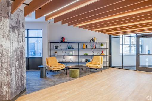 A room with a yellow chair and a wooden floor.