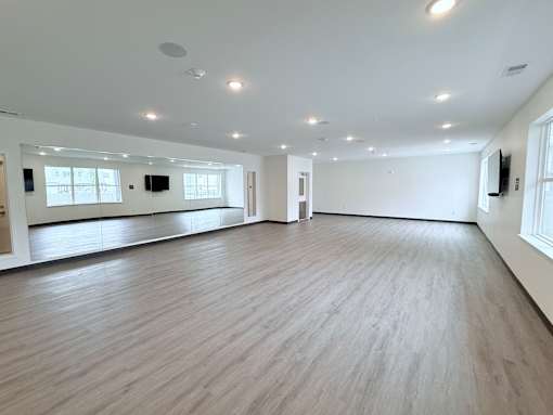 A spacious room with wooden flooring and white walls.