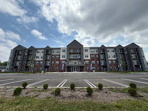 A large apartment complex with multiple buildings and a parking lot in front.