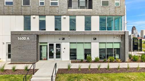 Modern apartment building entrance with landscaping at Union at Rivers Edge Apartments, Des Moines